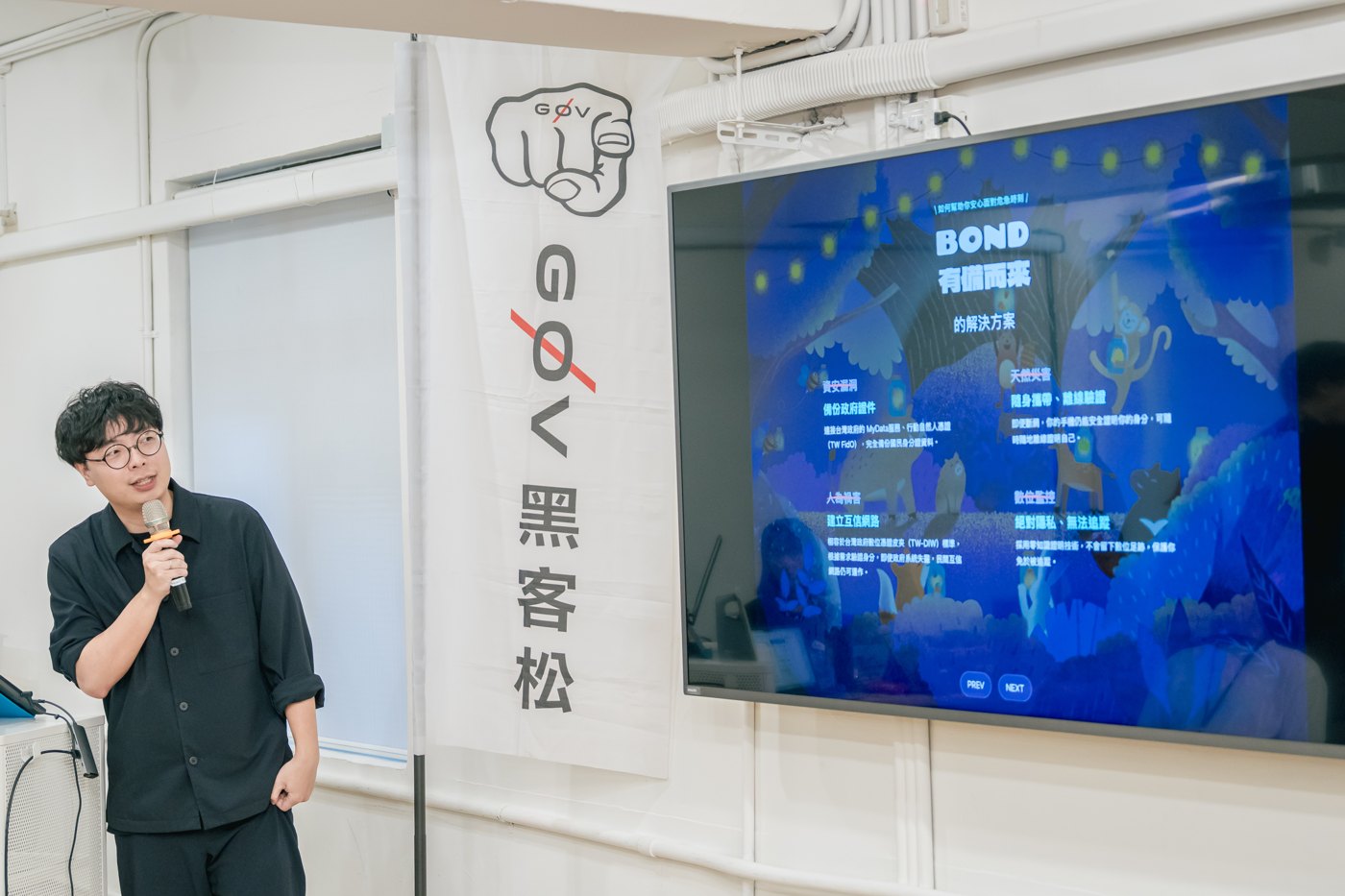 A speaker holds a microphone beside a projection showing BOND, its Chinese name, and a forest-animal visual.